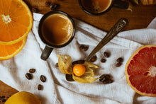  pamplemousse, orange et cerise de terre avec des grains de café et des espressos dans des tasses noires sur un linge blanc