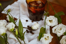  fleurs blanches avec grains de café sur linge blanc et café glacé dans un verre